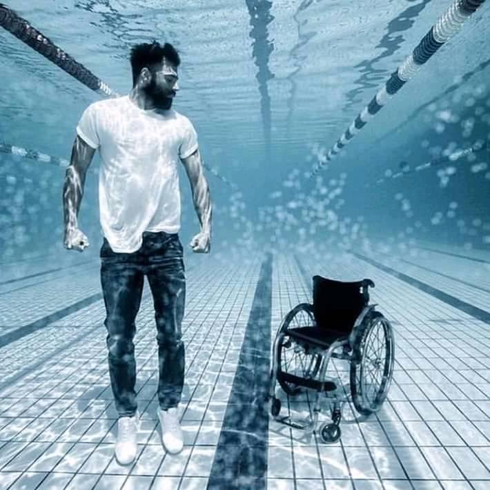 The meme features a photo of a man in a wheelchair, but with a twist: he's underwater. The image is captioned "When you finally get to the pool but you forgot your floaties".